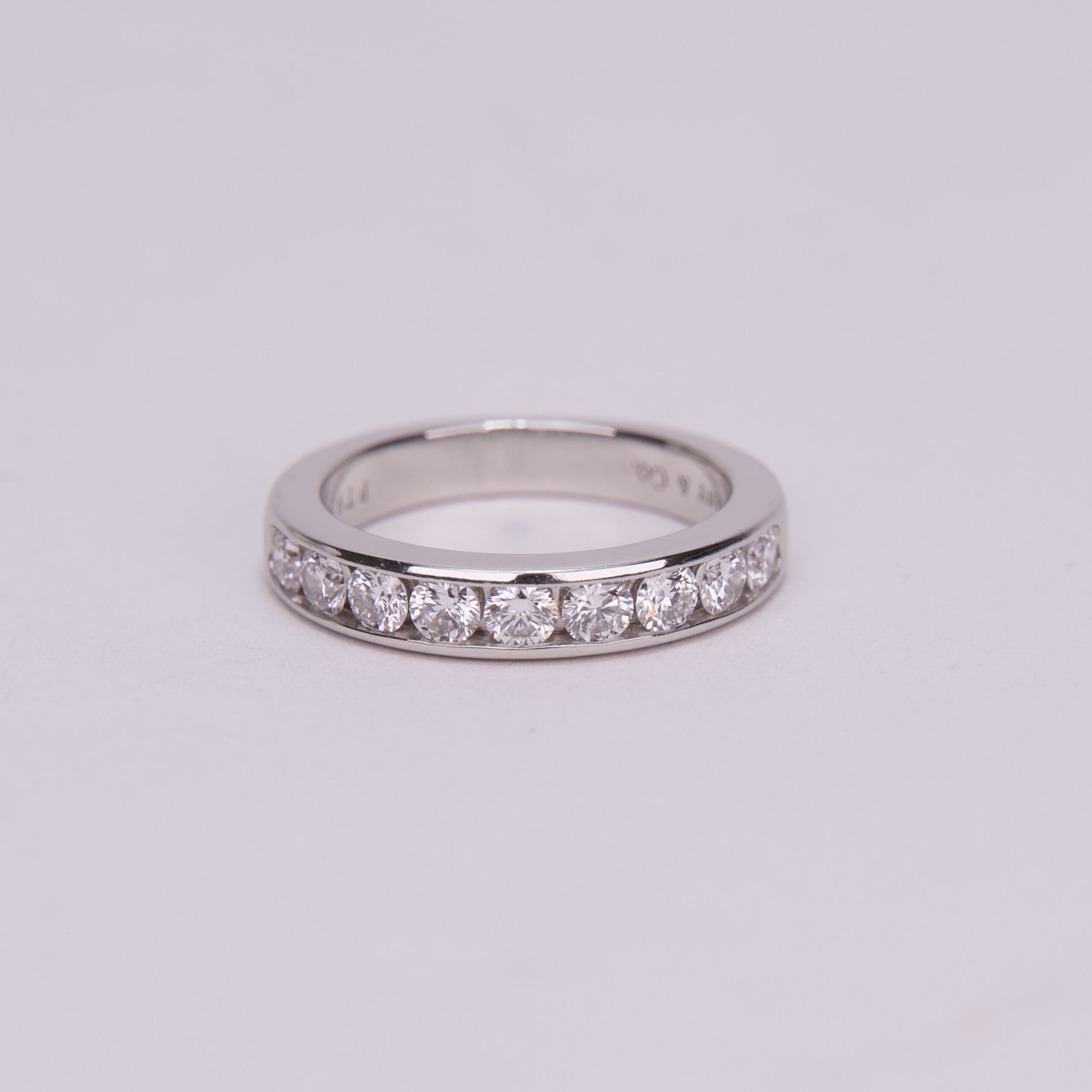 Silver diamond ring on plain background.