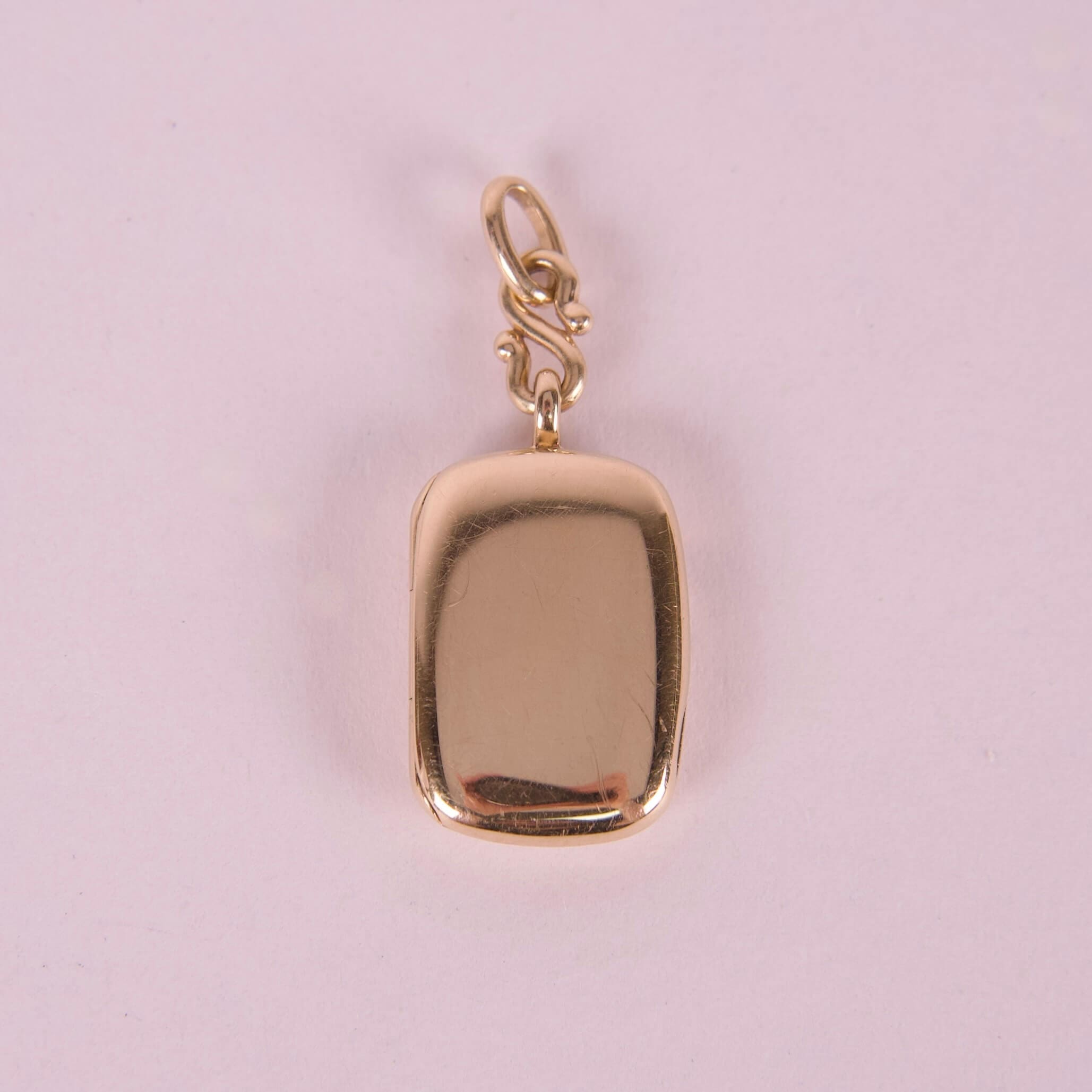 Gold rectangular pendant with attached loop.