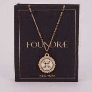 Gold pendant necklace on dark packaging box.