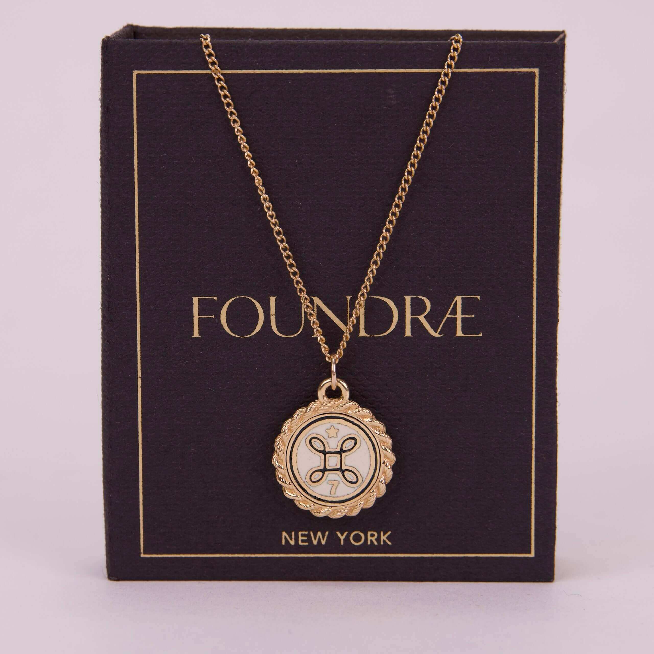 Gold pendant necklace on dark packaging box.