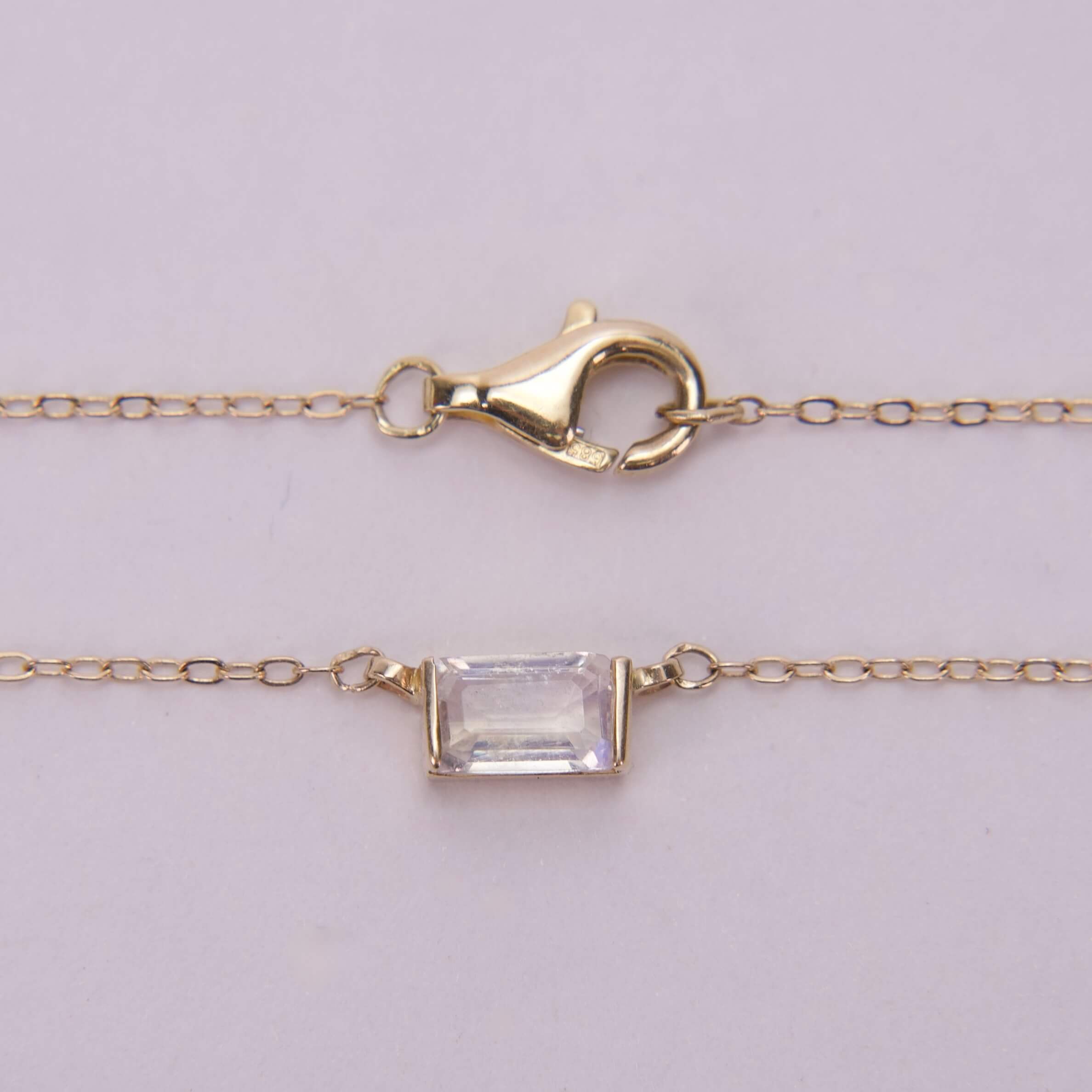 Gold chain with rectangular gemstone pendant.