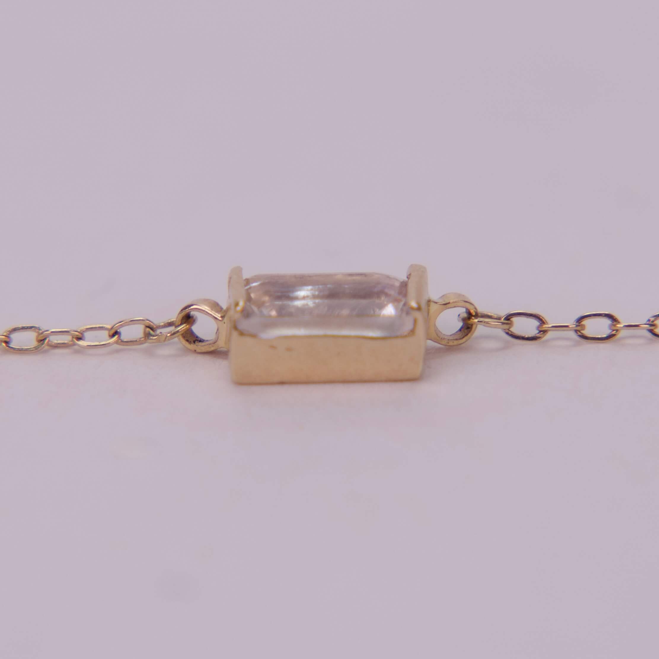 Gold chain with rectangular gemstone pendant.