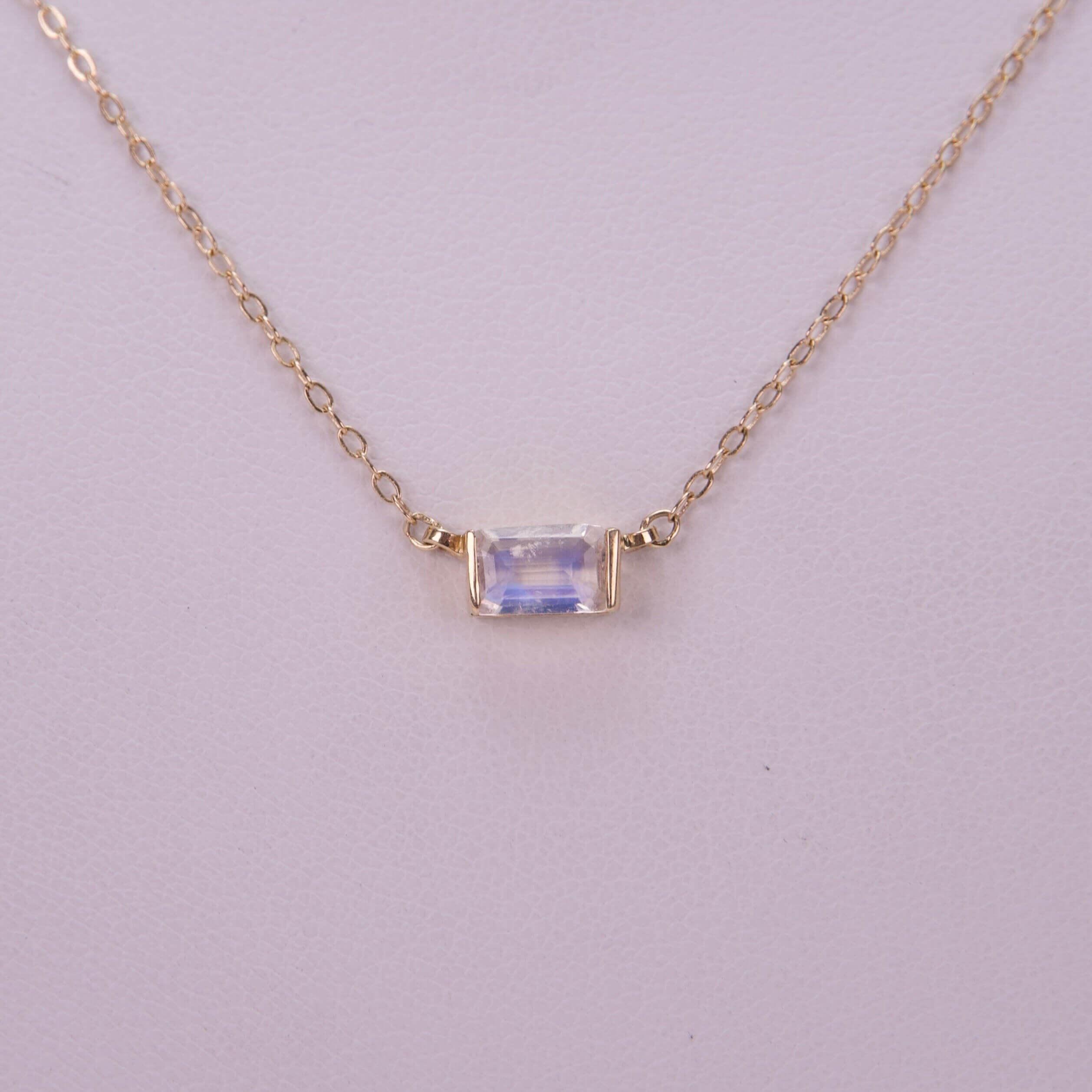 Gold necklace with rectangular gemstone pendant.