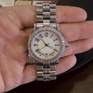 Silver wristwatch with diamond bezel on hand.