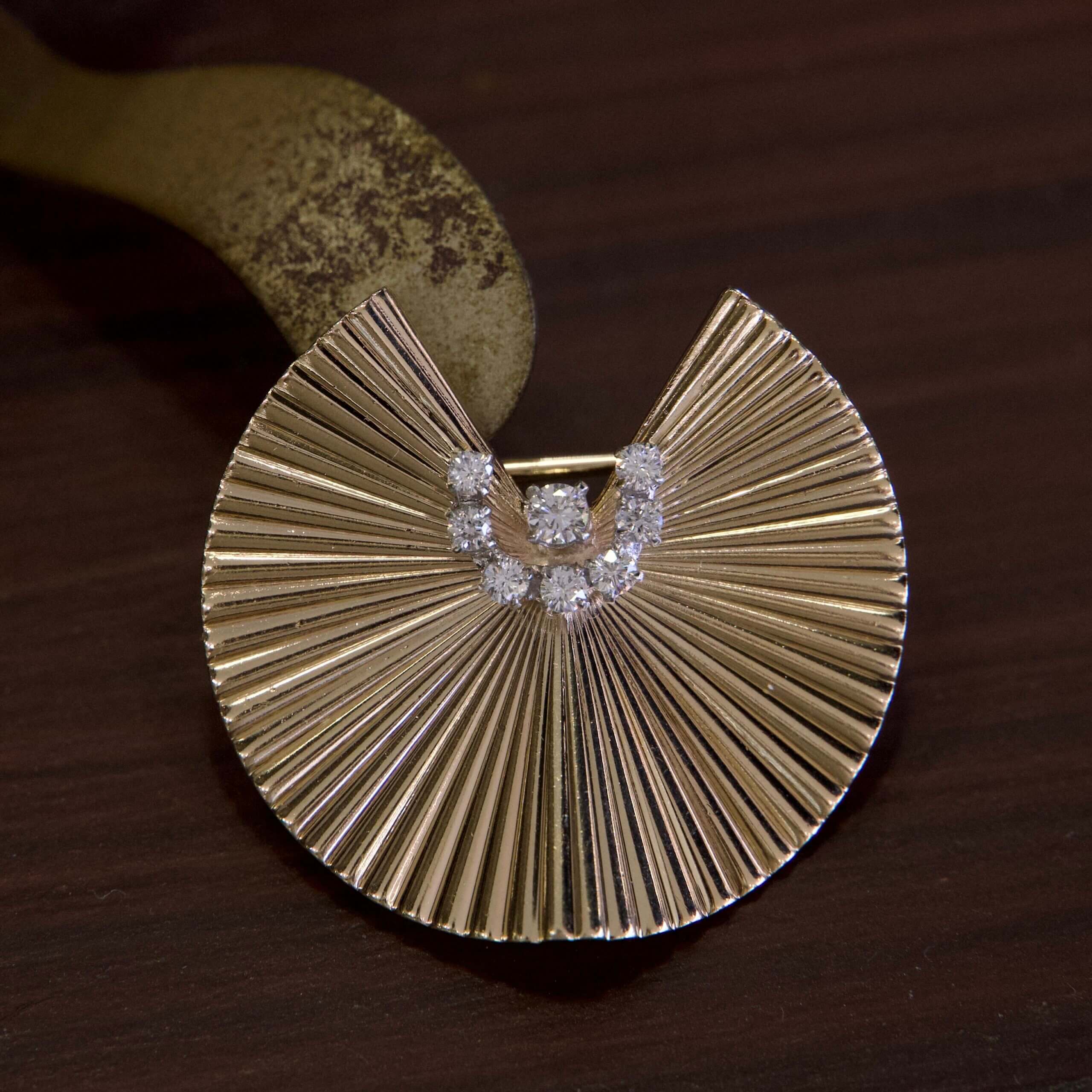 Gold fan-shaped brooch with diamonds.