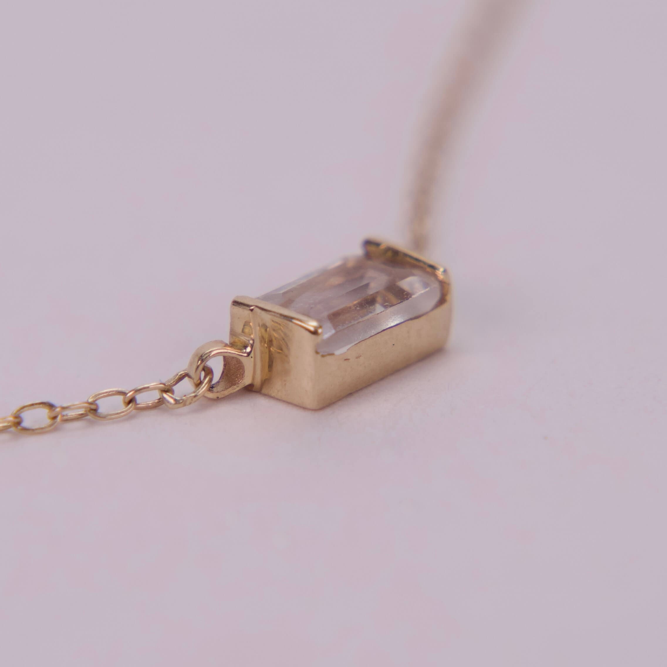 Gold chain with rectangular gemstone pendant.