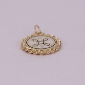 Gold pendant with decorative emblem design.