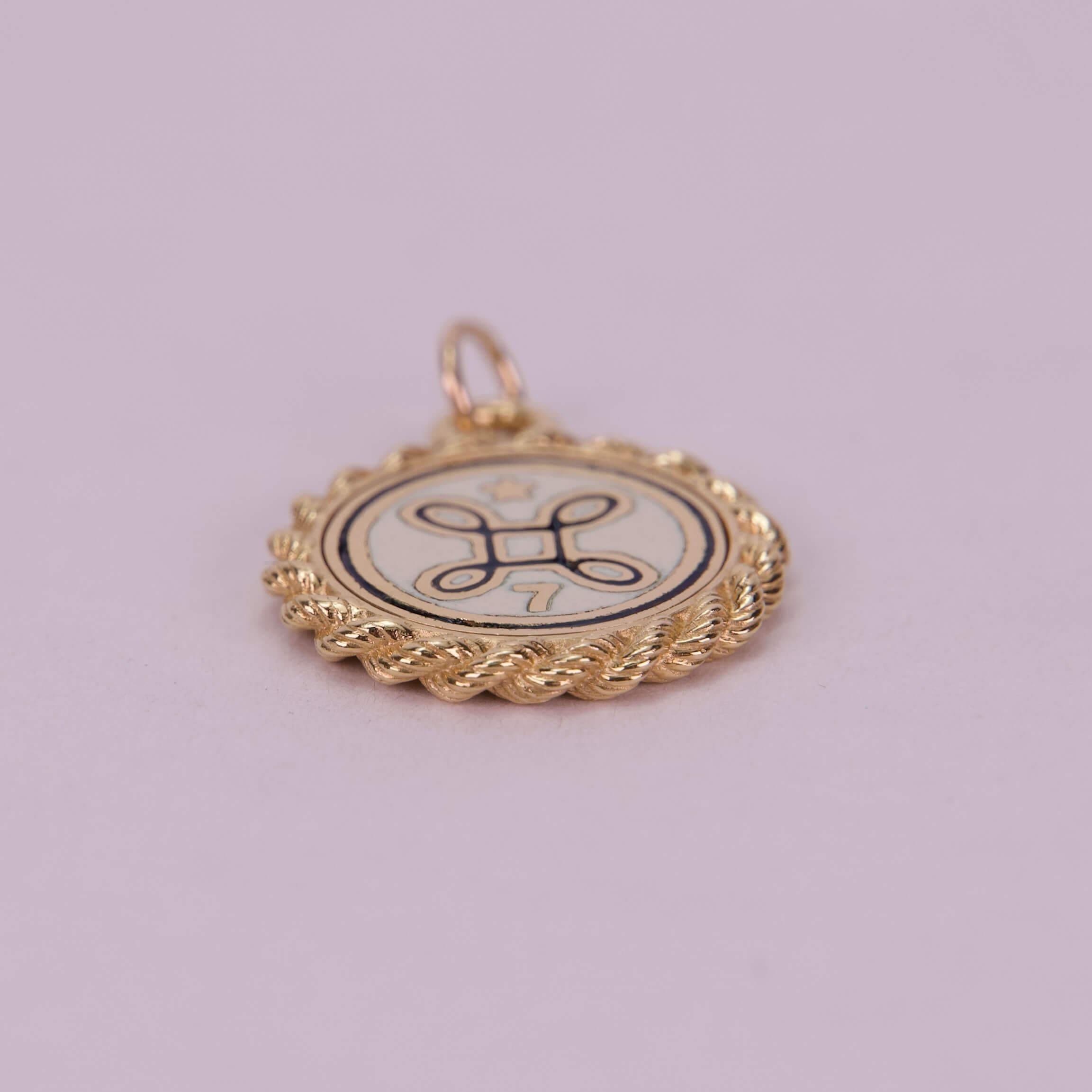 Gold pendant with decorative emblem design.