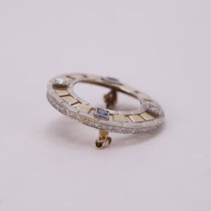 Vintage circular brooch with gemstone accents.