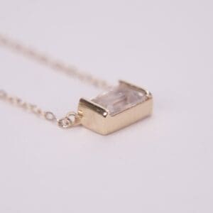 Gold pendant necklace with clear gemstone.