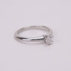 Silver ring with solitaire diamond on display.