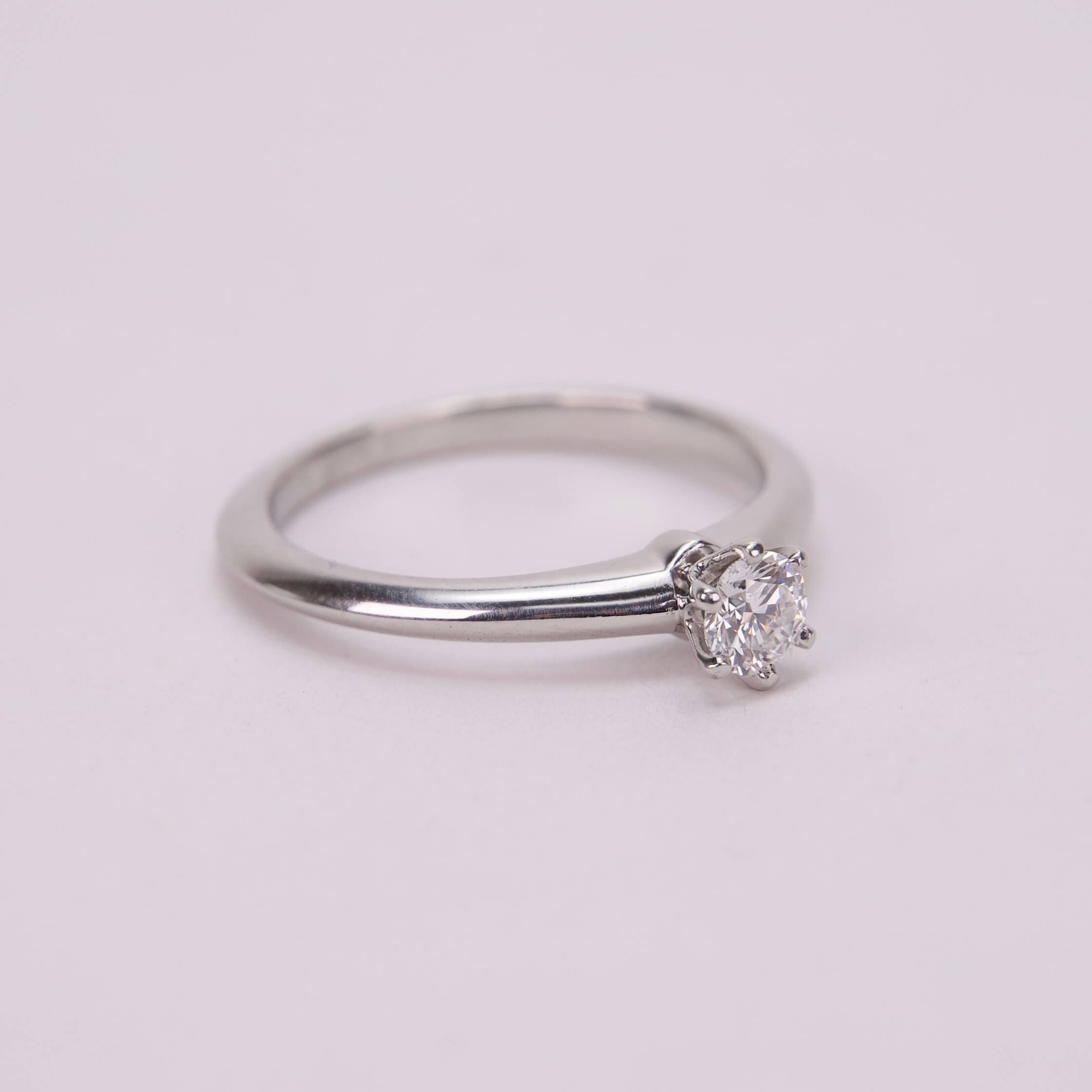 Silver ring with solitaire diamond on display.