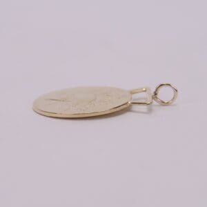 Gold pendant lying on a flat surface.