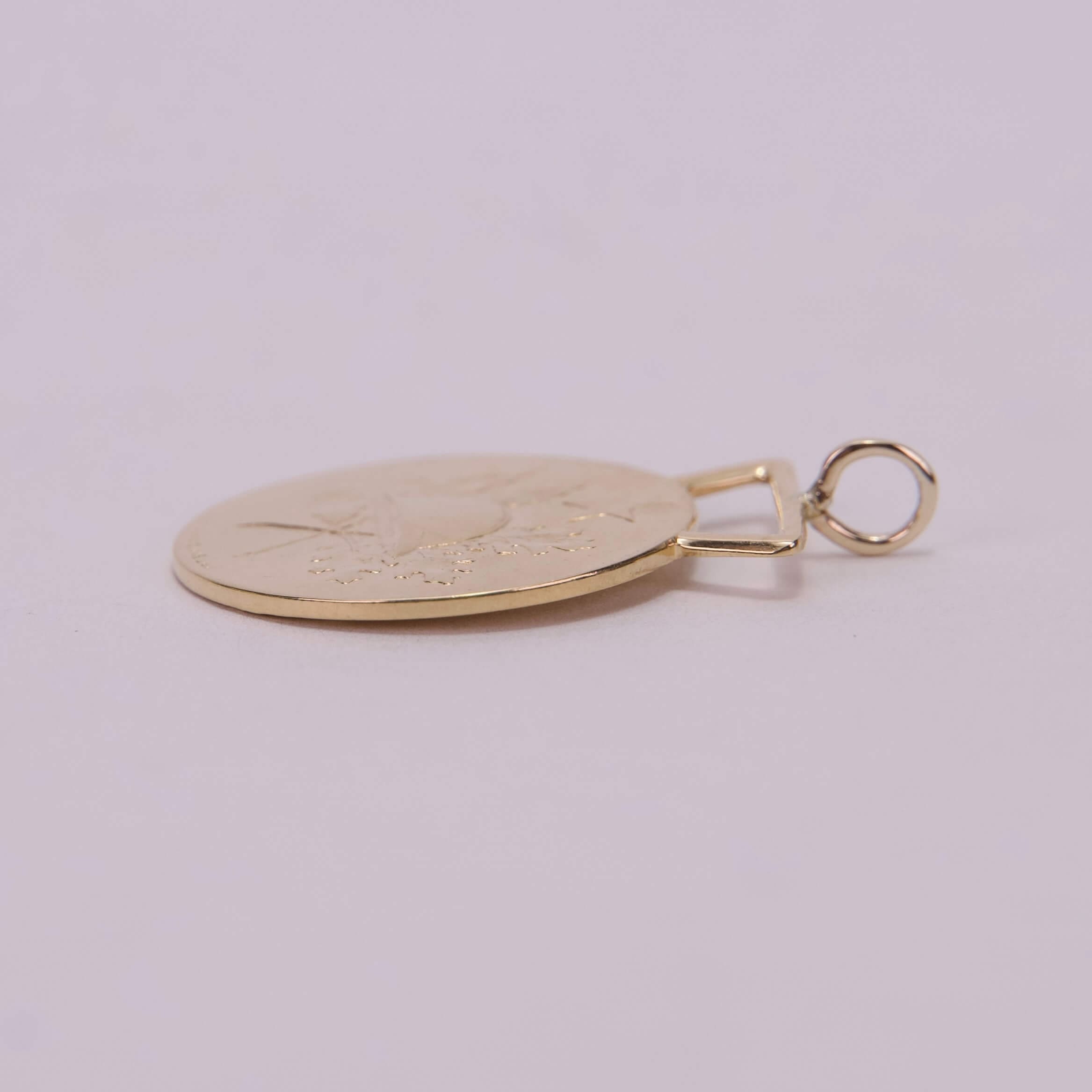 Gold pendant lying on a flat surface.