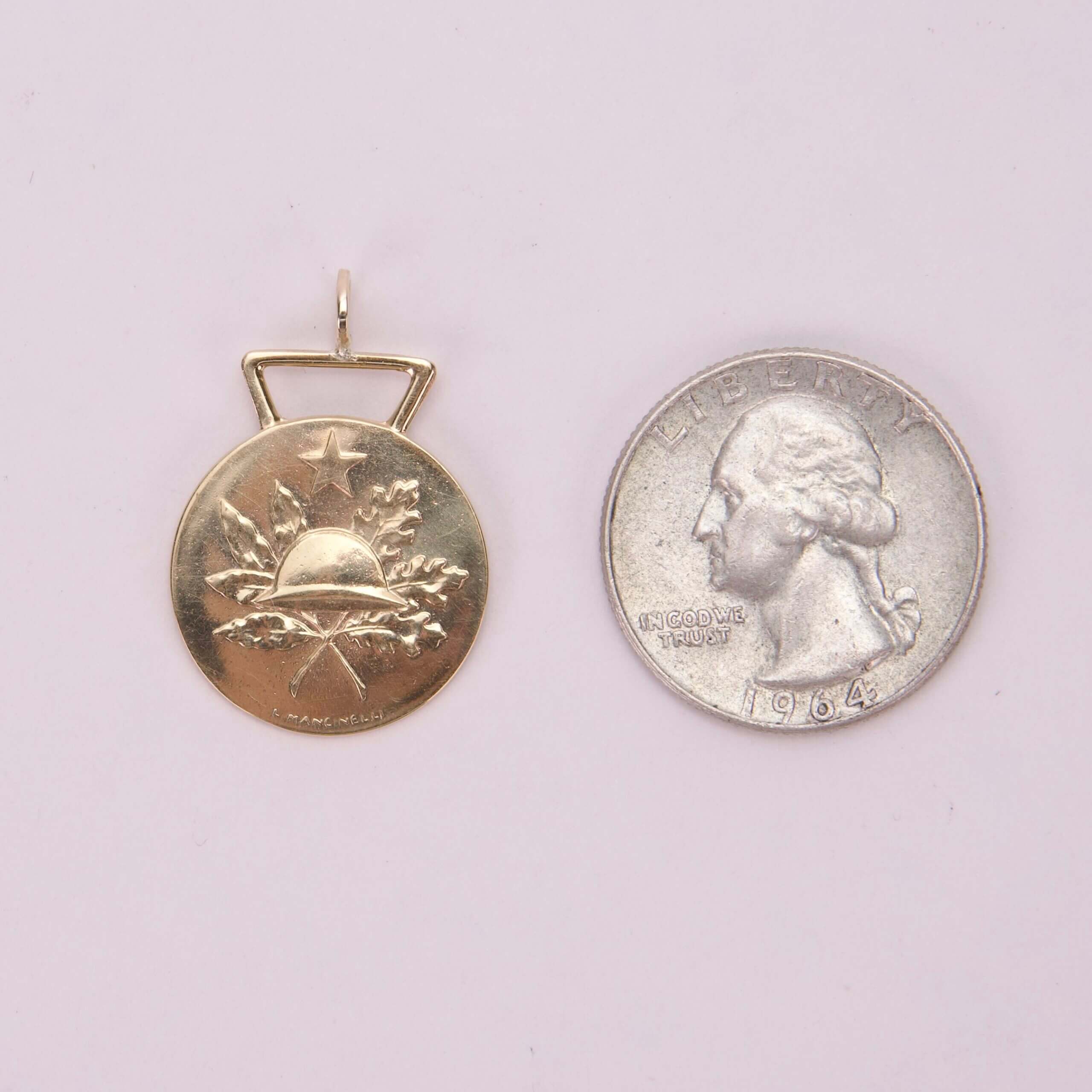 Gold pendant beside a 1964 quarter.