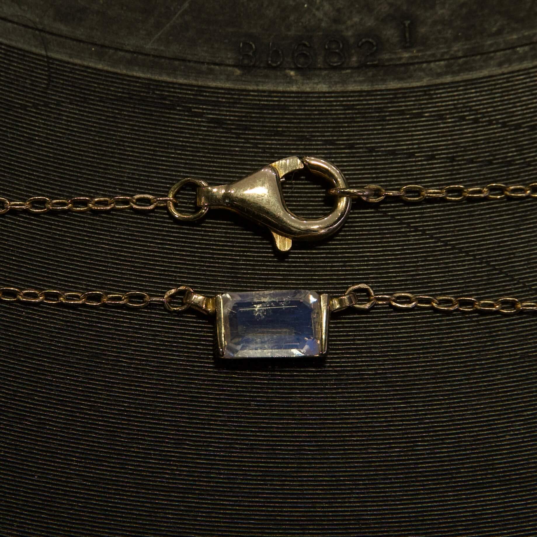 Gold chain with gemstone and clasp.
