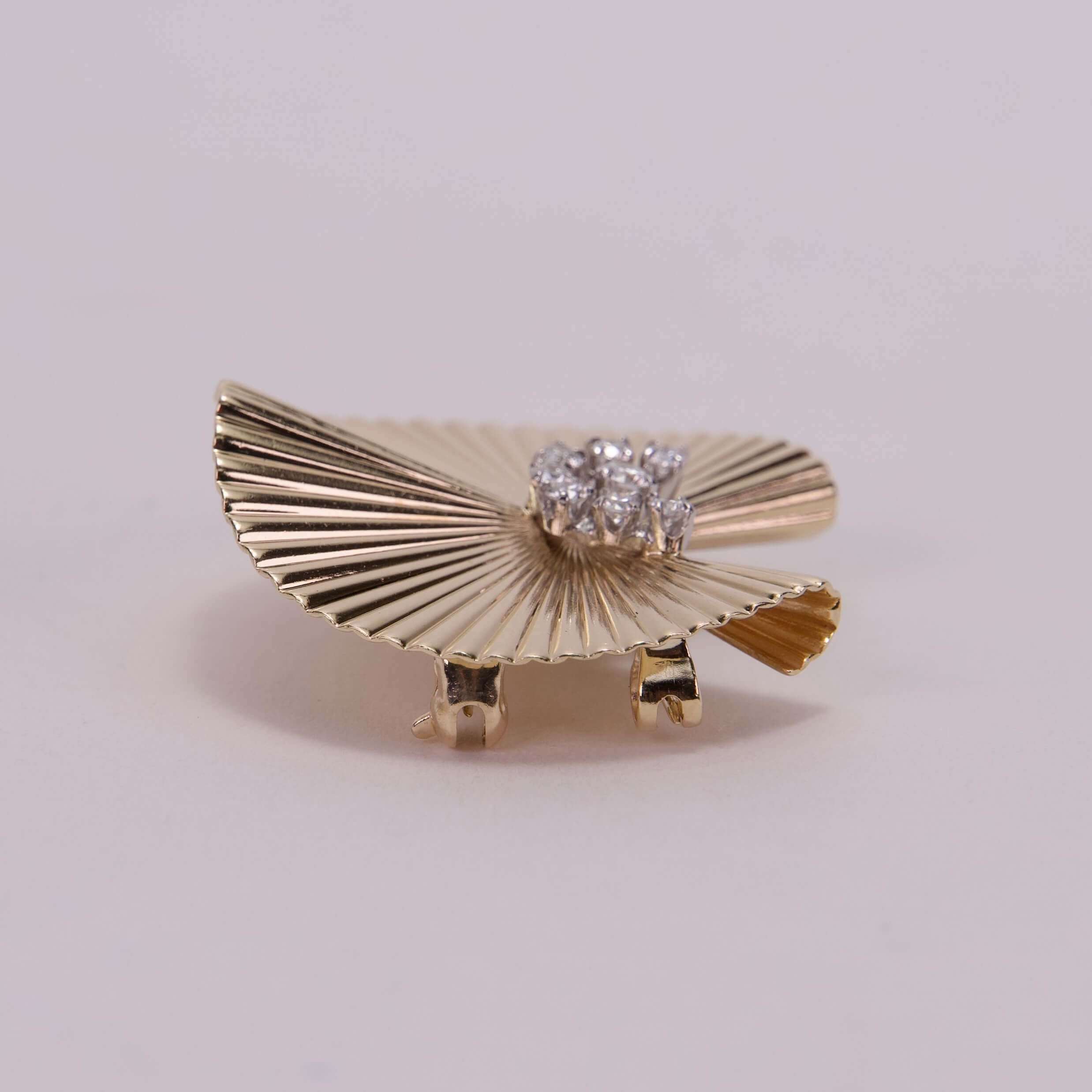 Gold fan-shaped brooch with diamonds.