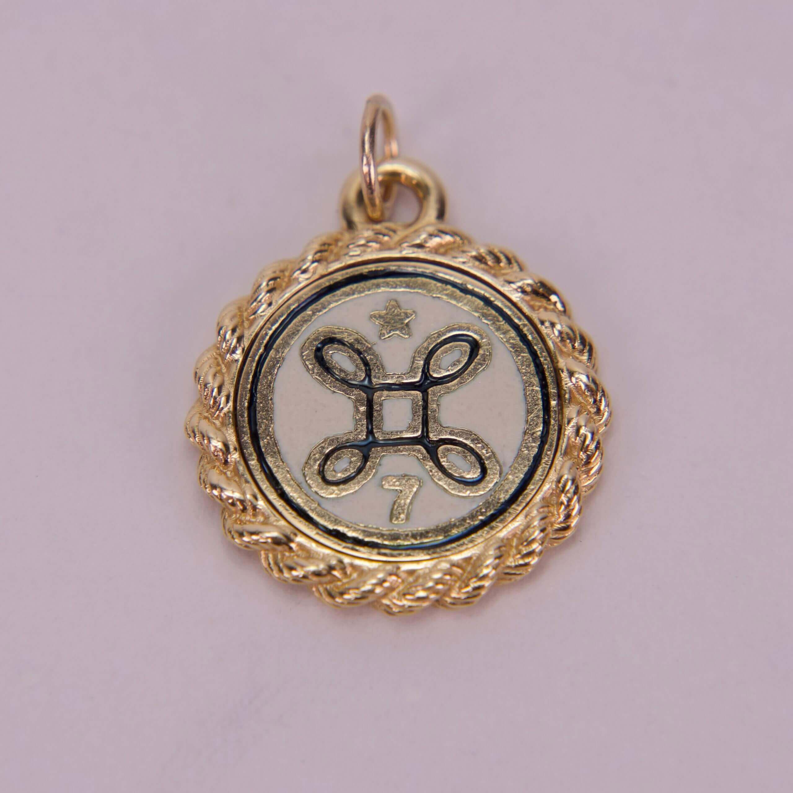 Gold pendant with star and decorative symbol.