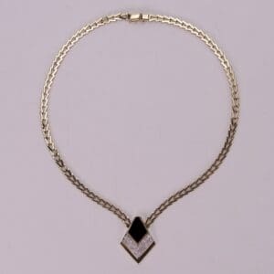 Gold necklace with black and white pendant.