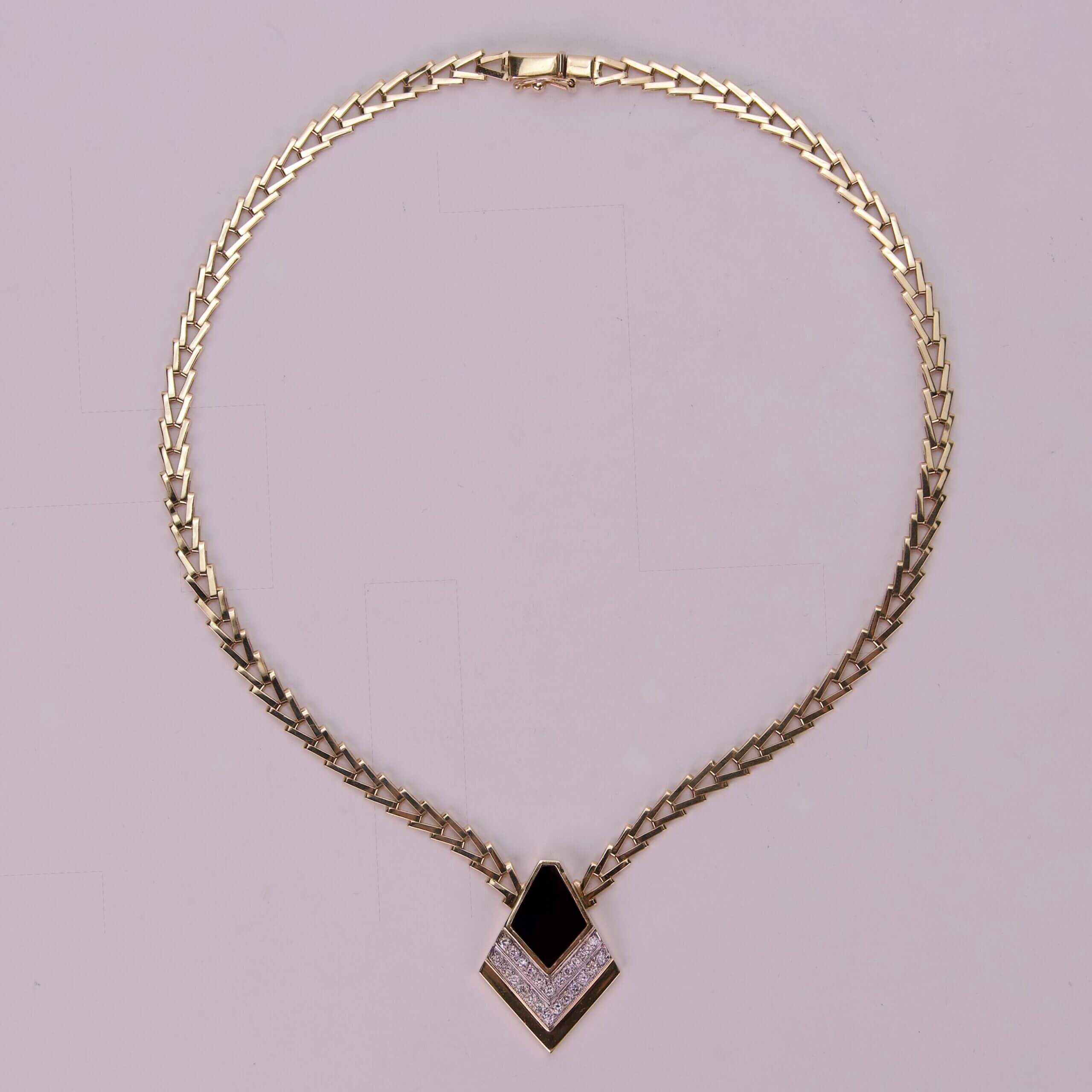 Gold necklace with black and white pendant.