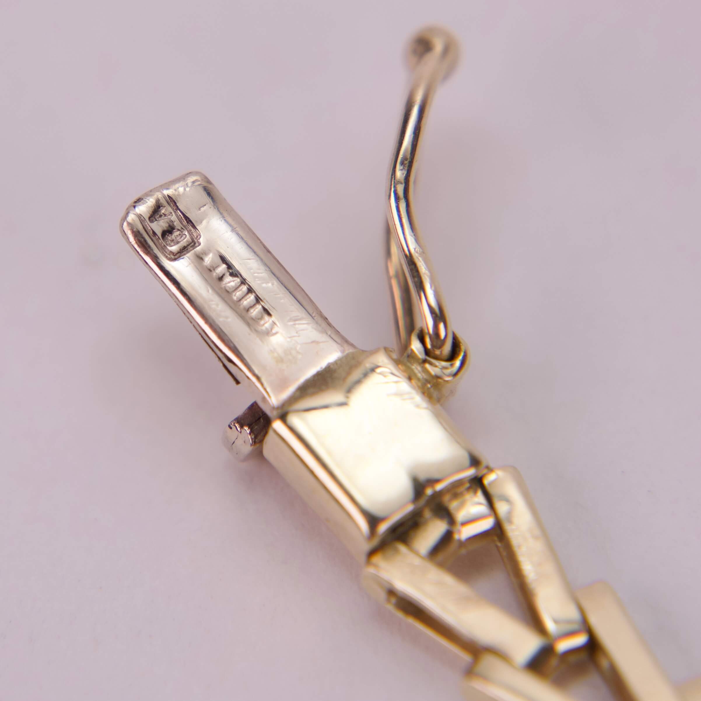 Gold jewelry clasp with intricate detailing.