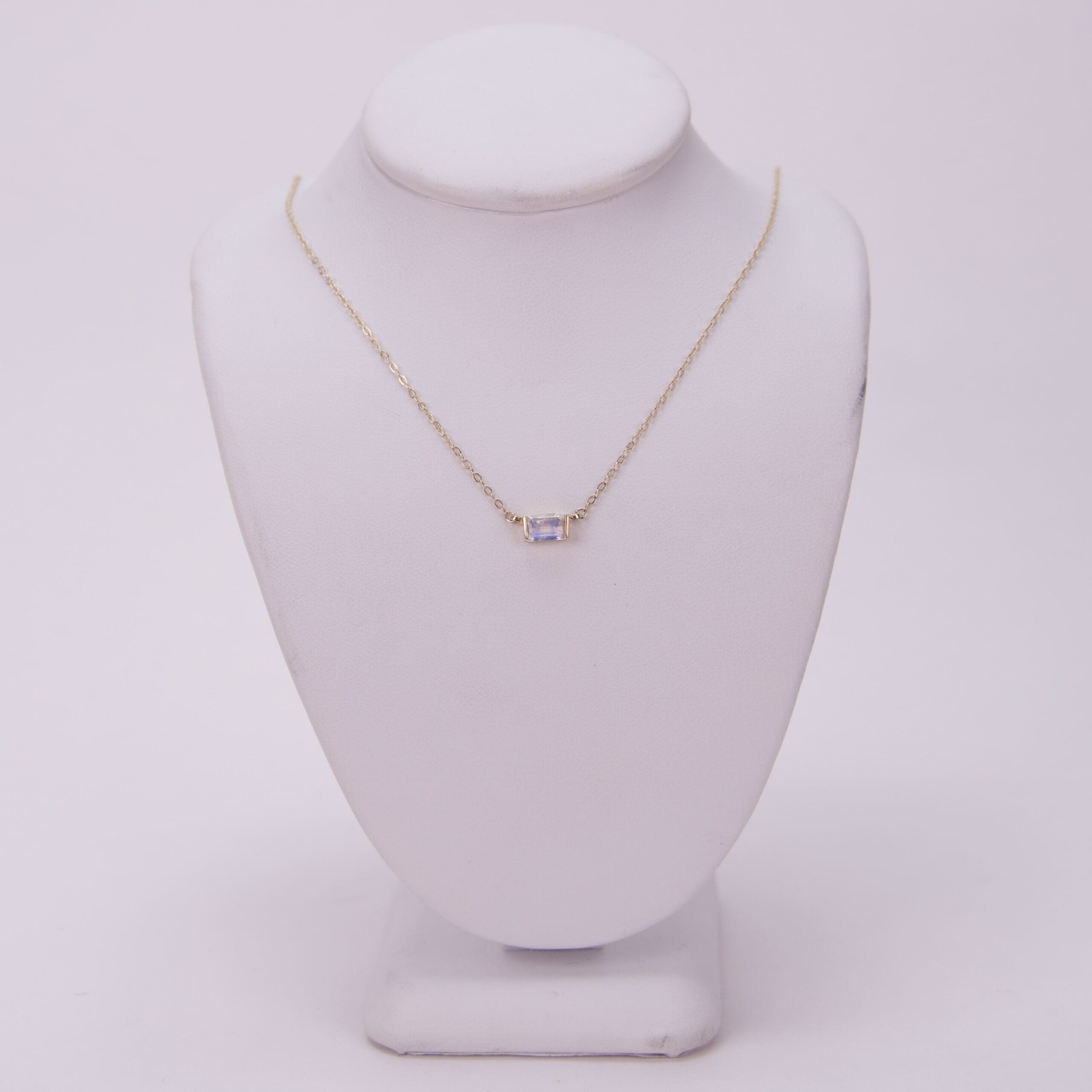 Gold necklace with small rectangular pendant.