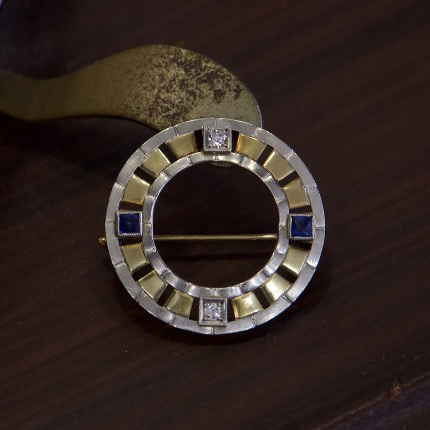 Circular brooch with gold and blue accents.