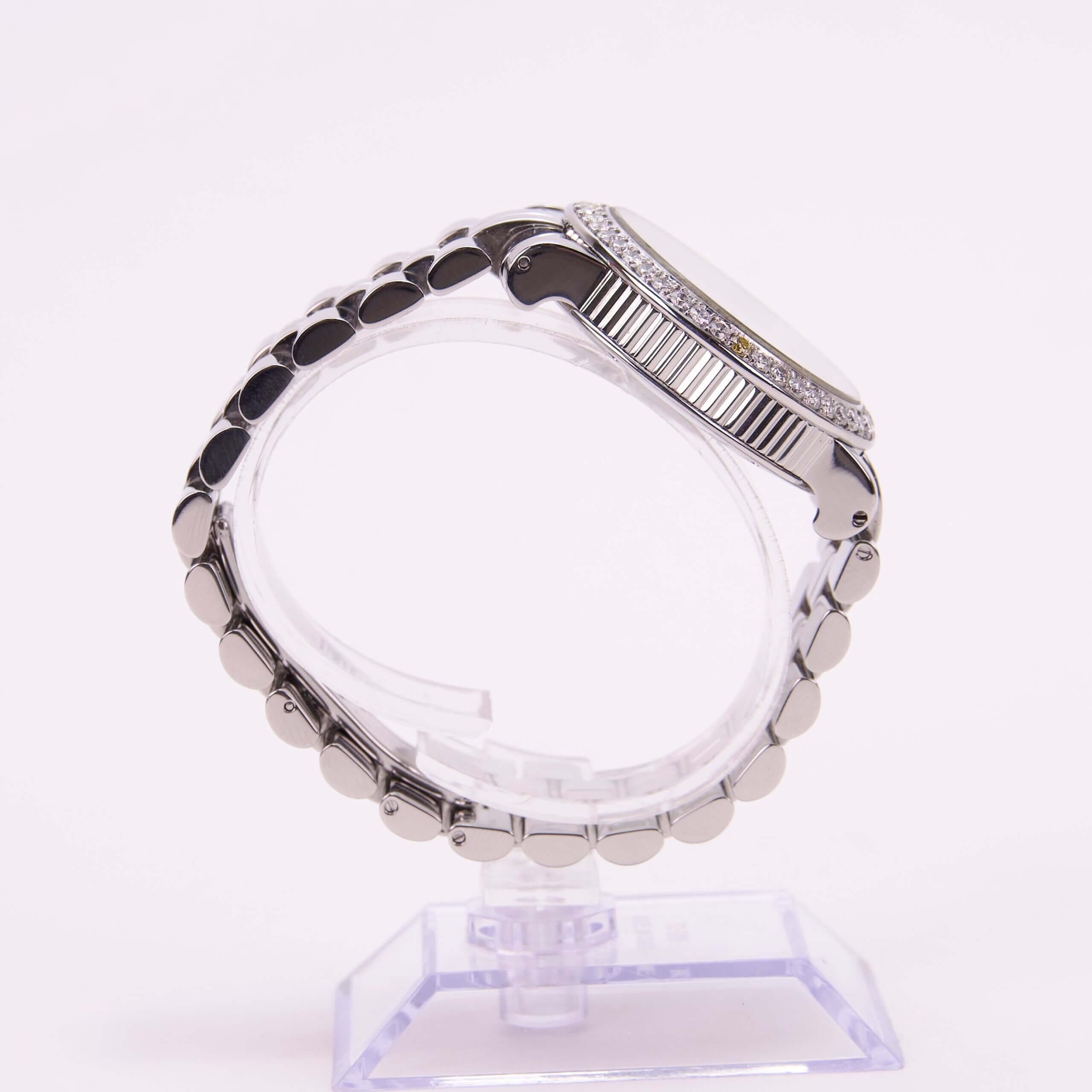 Silver wristwatch on a clear stand.