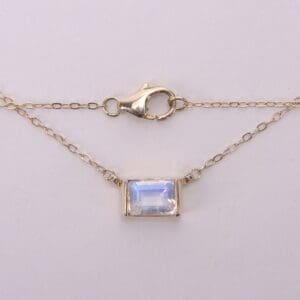 Gold chain with rectangular gemstone pendant.