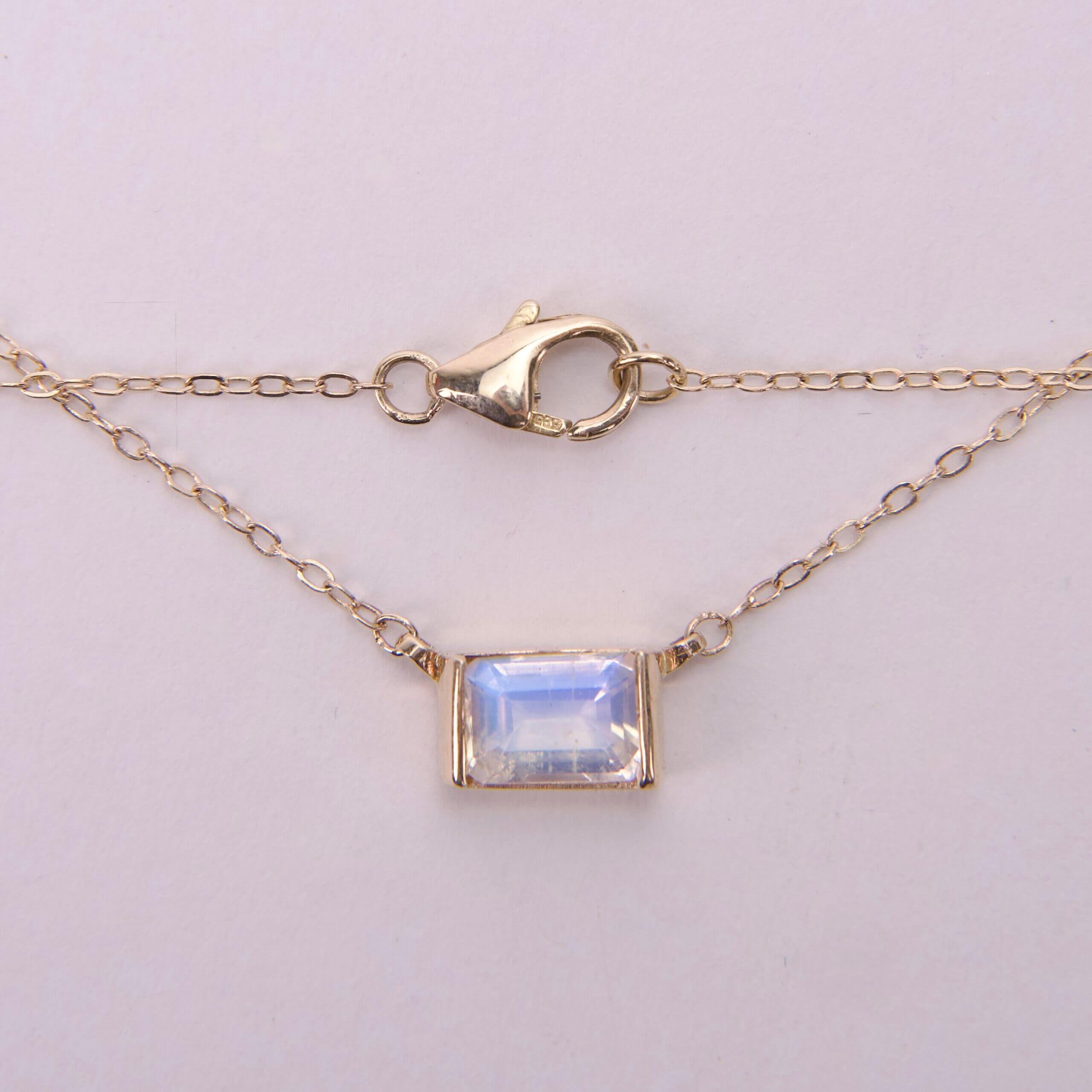 Gold chain with rectangular gemstone pendant.