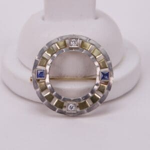 Circular brooch with blue and clear gems.