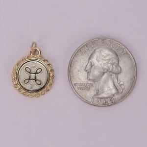 Gold pendant next to a quarter coin.