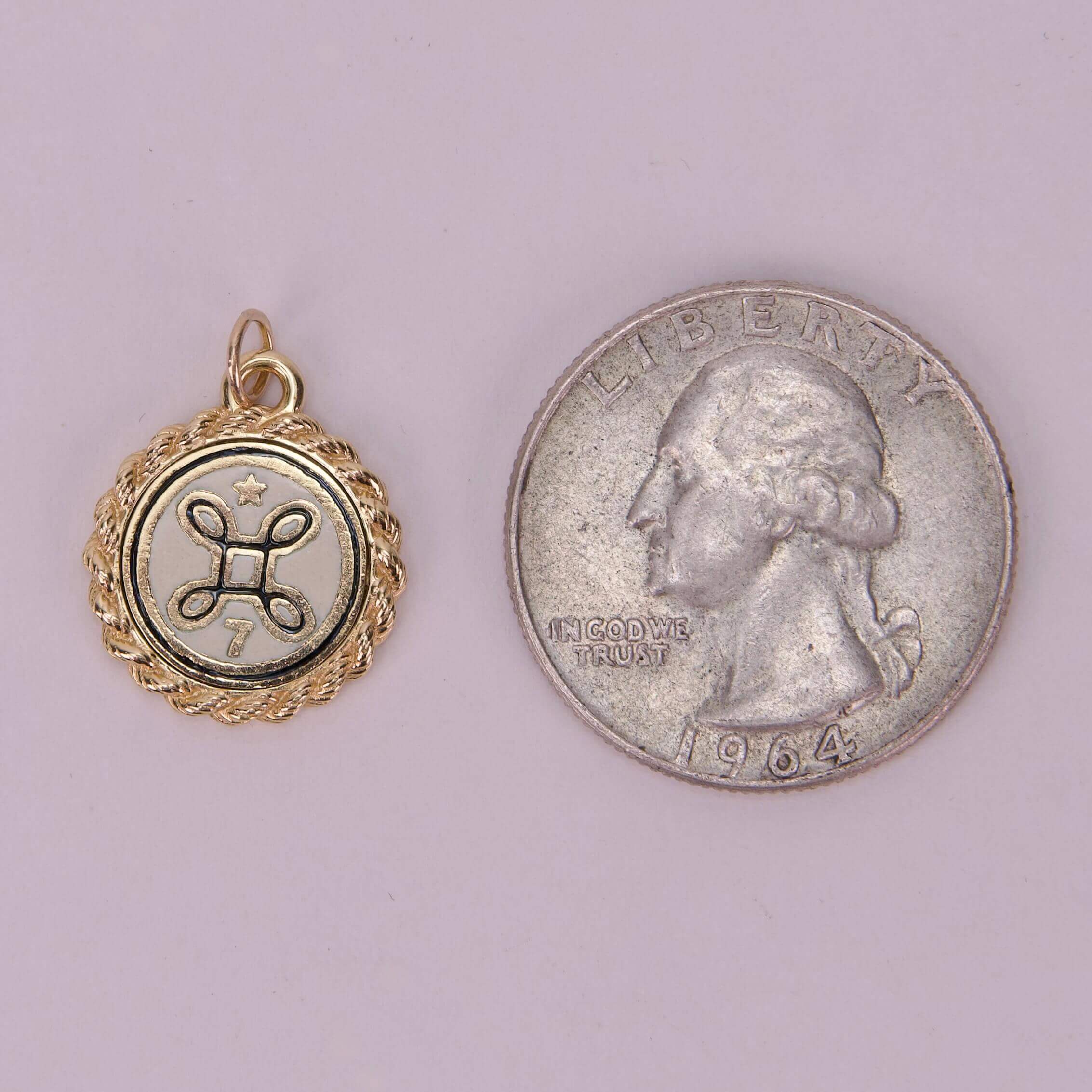 Gold pendant next to a quarter coin.