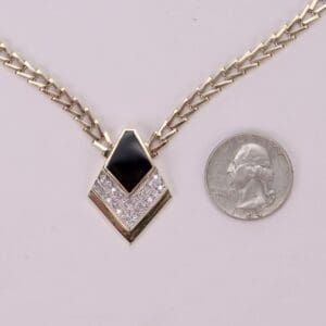 Gold necklace with black pendant and quarter.