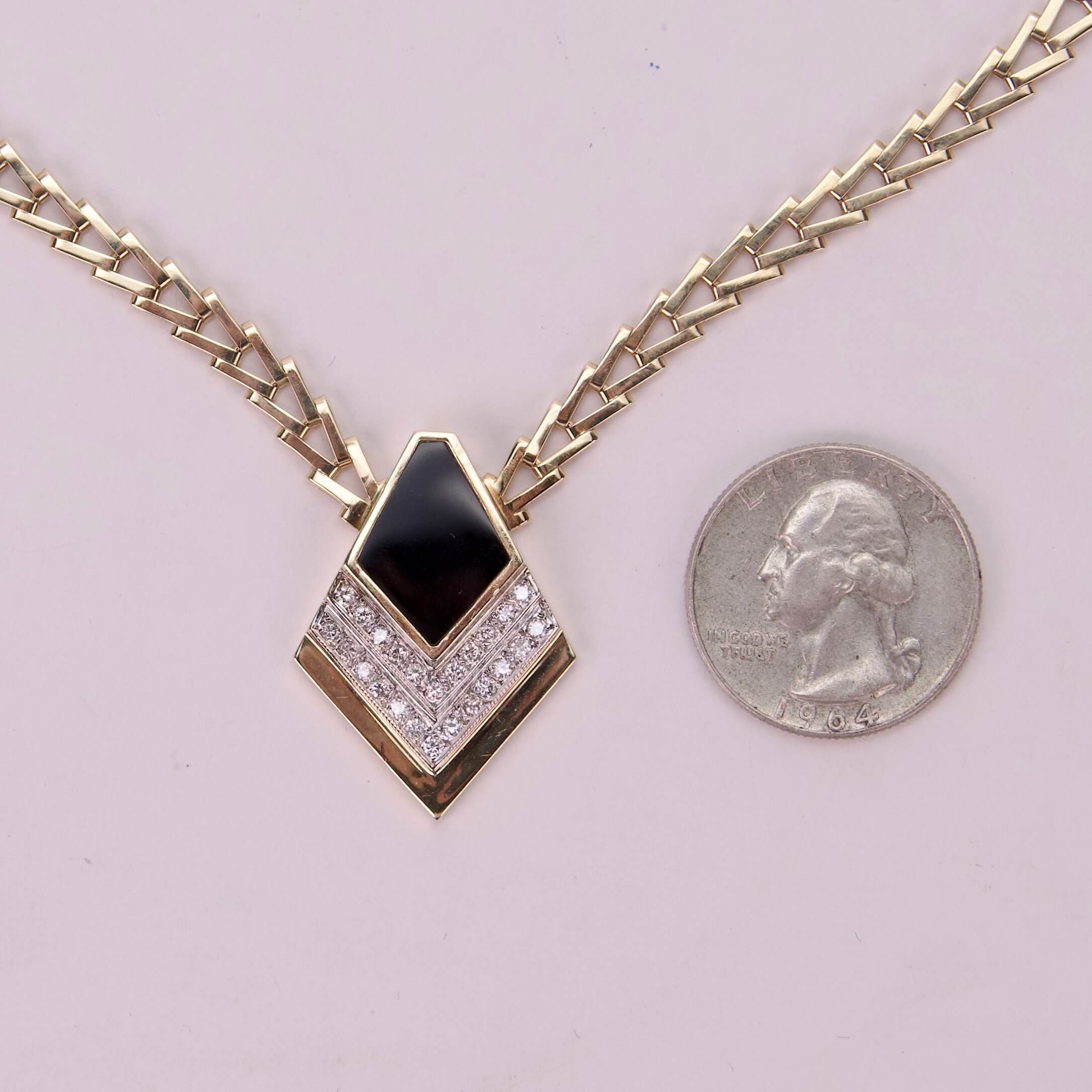 Gold necklace with black pendant and quarter.