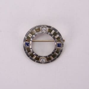 Circular brooch with blue and white stones.