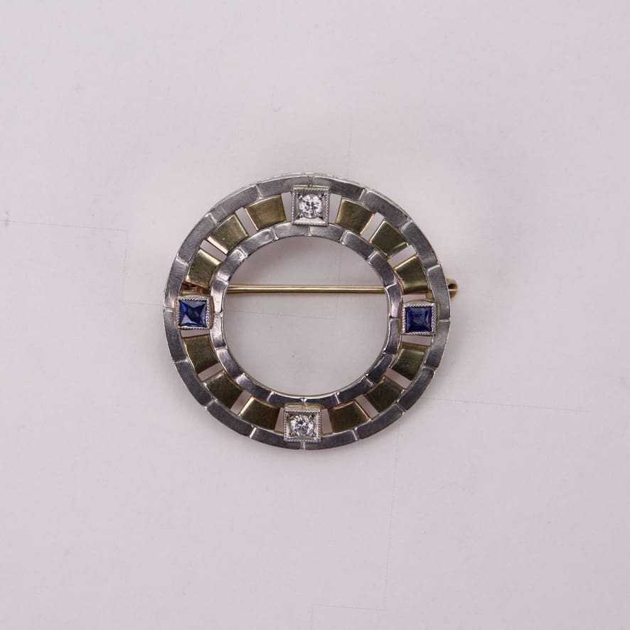 Circular brooch with blue and white stones.