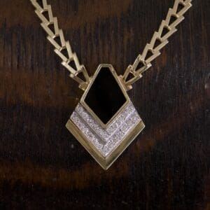 Gold necklace with black and silver pendant.