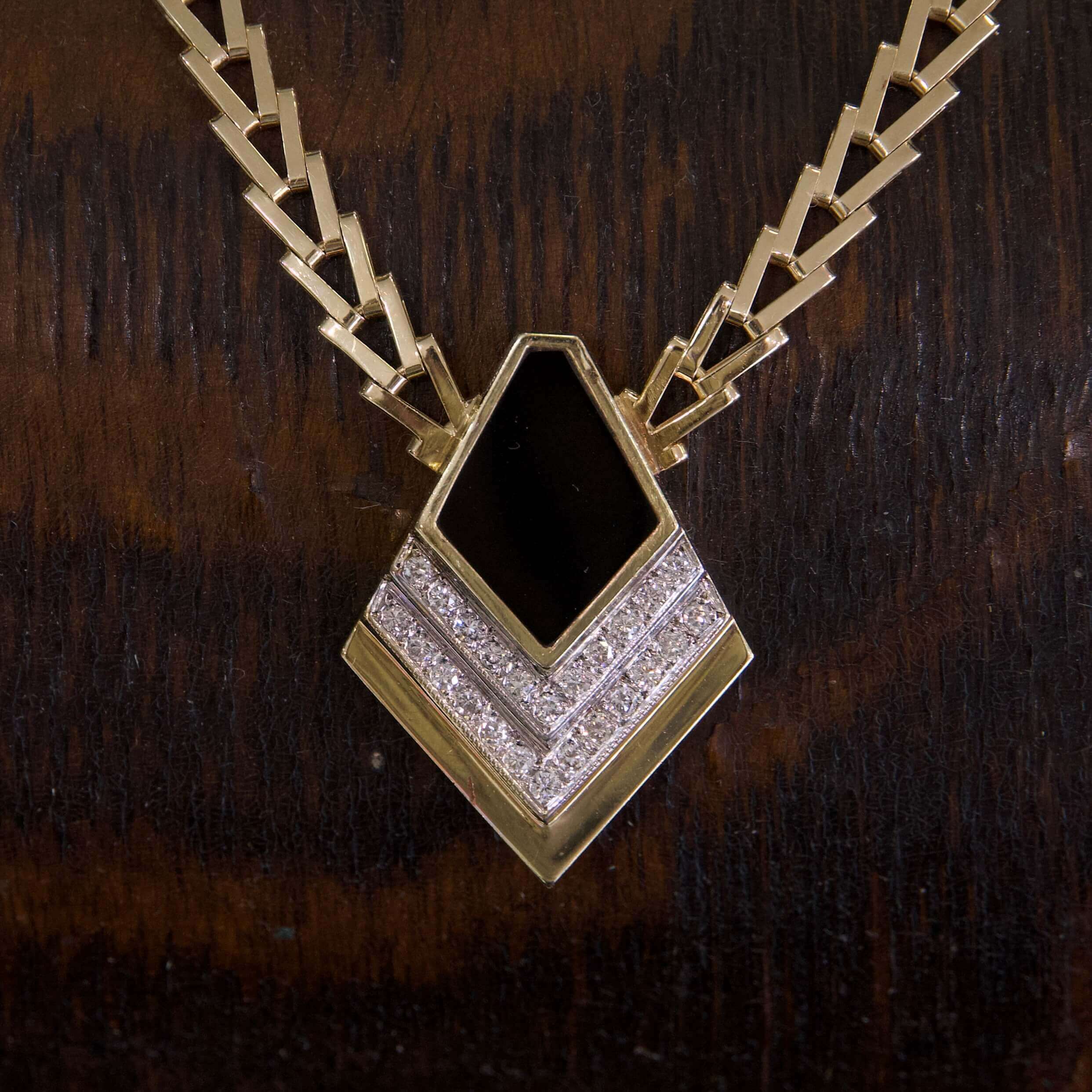 Gold necklace with black and silver pendant.