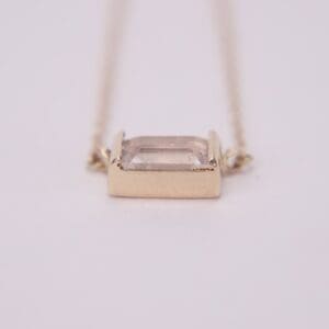 Gold necklace with rectangular gemstone pendant.
