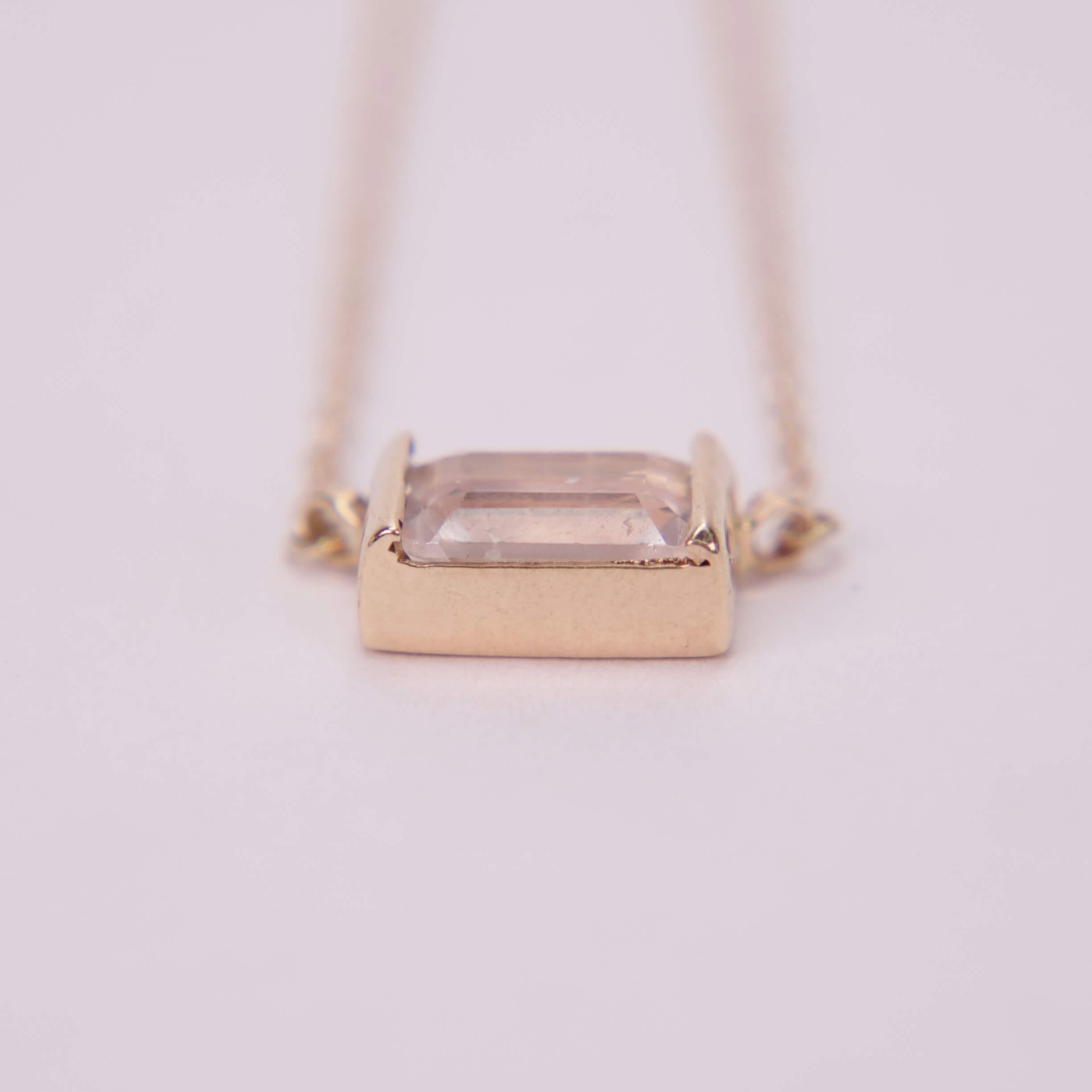 Gold necklace with rectangular gemstone pendant.