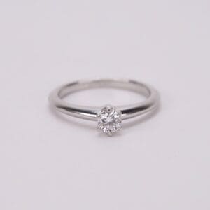Diamond solitaire ring on white background.