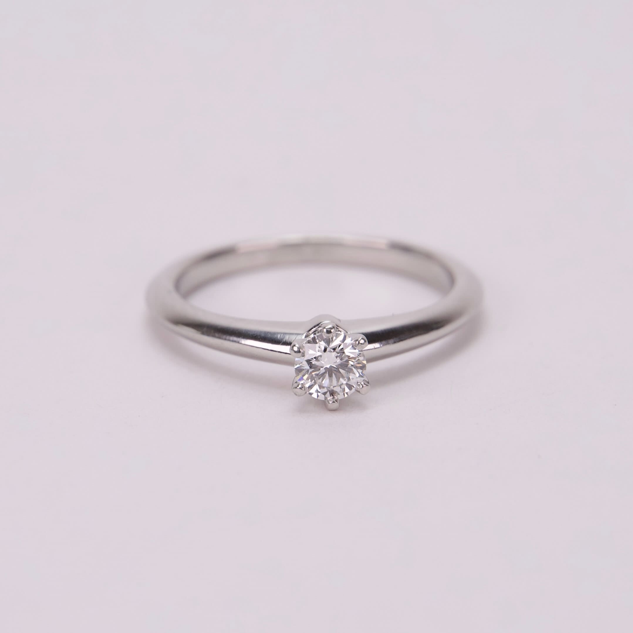 Diamond solitaire ring on white background.
