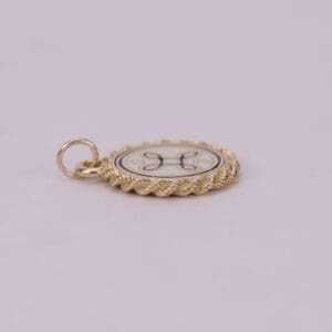Gold circular pendant with decorative design.