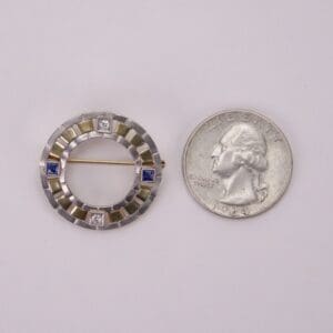 Circular brooch beside a U.S. quarter.