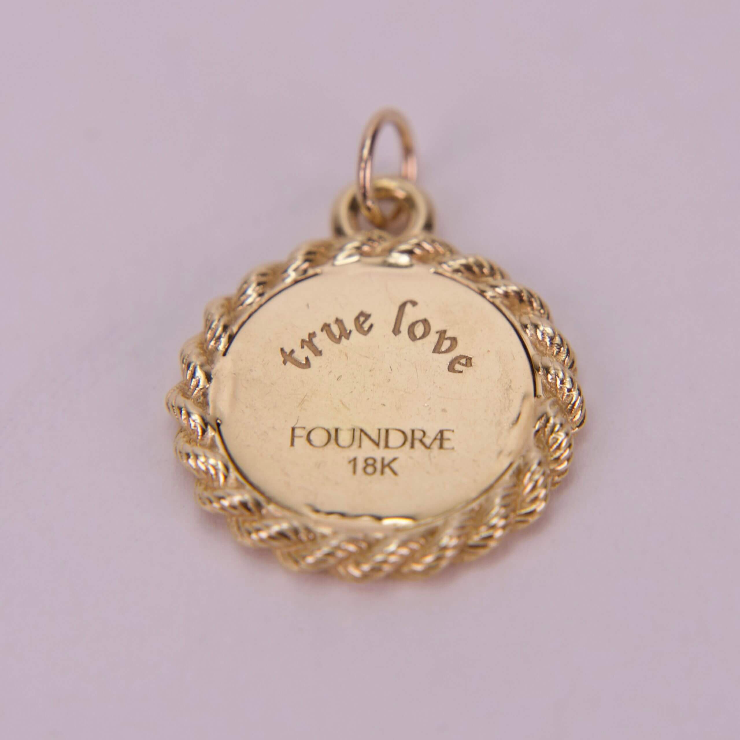 Gold pendant with "true love" engraving.