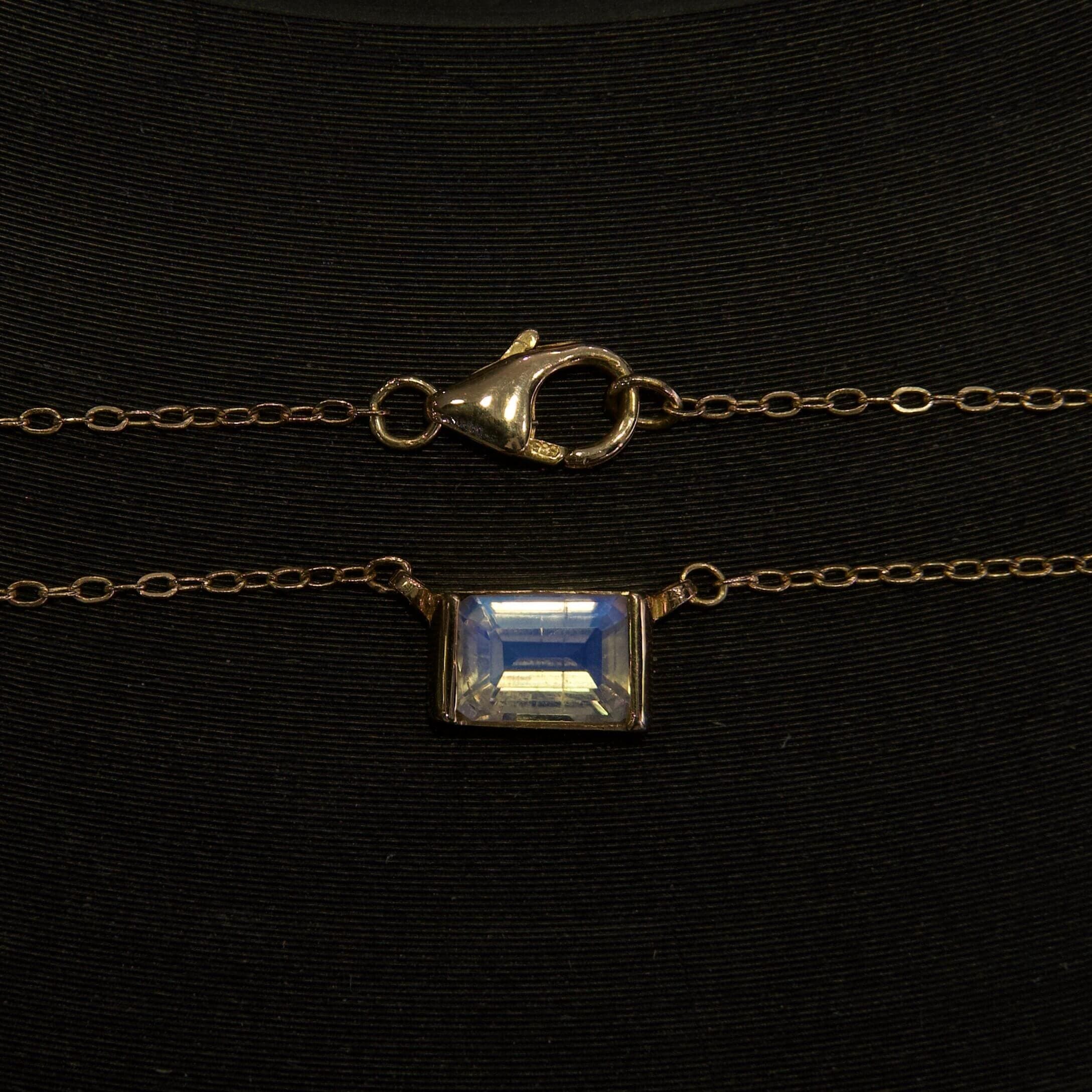 Gold chain with clasp and gemstone pendant.