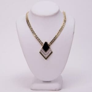 Gold necklace with black and white pendant.