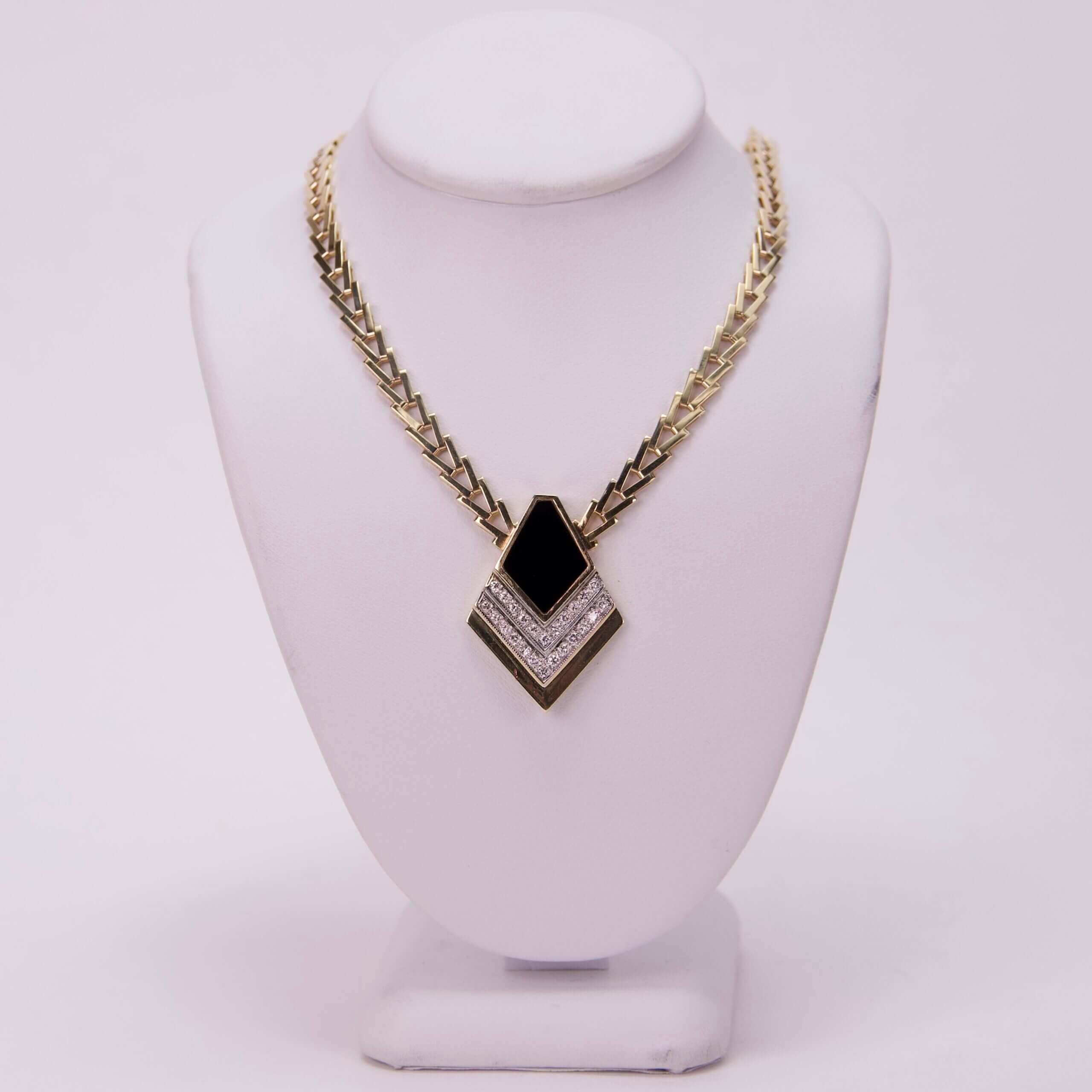 Gold necklace with black and white pendant.