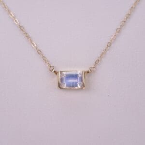 Gold chain necklace with rectangular gemstone.